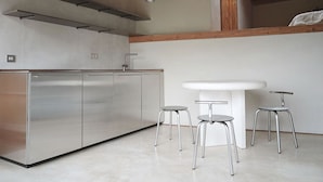 Une cuisine moderne avec des meubles en acier inoxydable, un évier blanc et des tabourets.