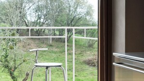 Un balcon avec une chaise en métal et une vue sur les arbres.