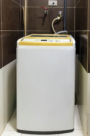 A compact, white and yellow water heater in a corner with a wall-mounted control panel and a visible plumbing connection. - Porlamar Work & Stay Apartment with pool and WIFI (Porlamar)