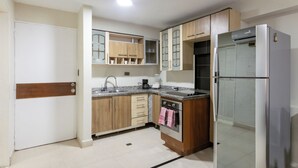 A kitchen with wooden cabinets, a built-in oven, a refrigerator, and a granite countertop.