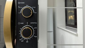 Eine Mikrowelle mit zwei Drehreglern, einem Timer und einer Auftau-Einstellung.