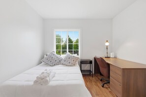Ein Schlafzimmer mit einem Bett, einem Schreibtisch und einem Fenster.