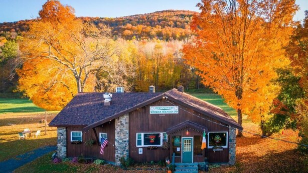 A rustic stone building with a sign for Windham Mountain Inn, surrounded by autumn foliage. - Jimmy OConnors Windham Mountain Inn (Windham)