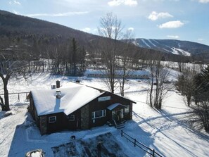 A lodge with a snow-covered roof, a wooden exterior, and a sign indicating it is a mountain resort.