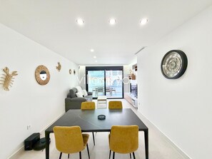 Ein modernes Wohnzimmer mit Essbereich, einer Couch und einem großen Fenster.