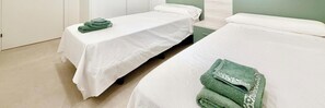 Ein Hotelzimmer mit zwei Einzelbetten, einem kleinen Tisch und einem grünen Handtuch auf einem Bett.
