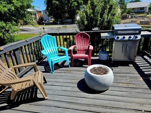 En terrasse med Adirondack-stole, grill og en stor plantekasse.