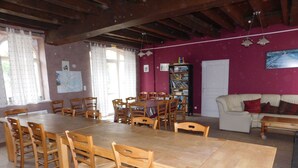 Un comedor con una gran mesa de madera y sillas, una estantería, un sofá y un mapa en la pared.