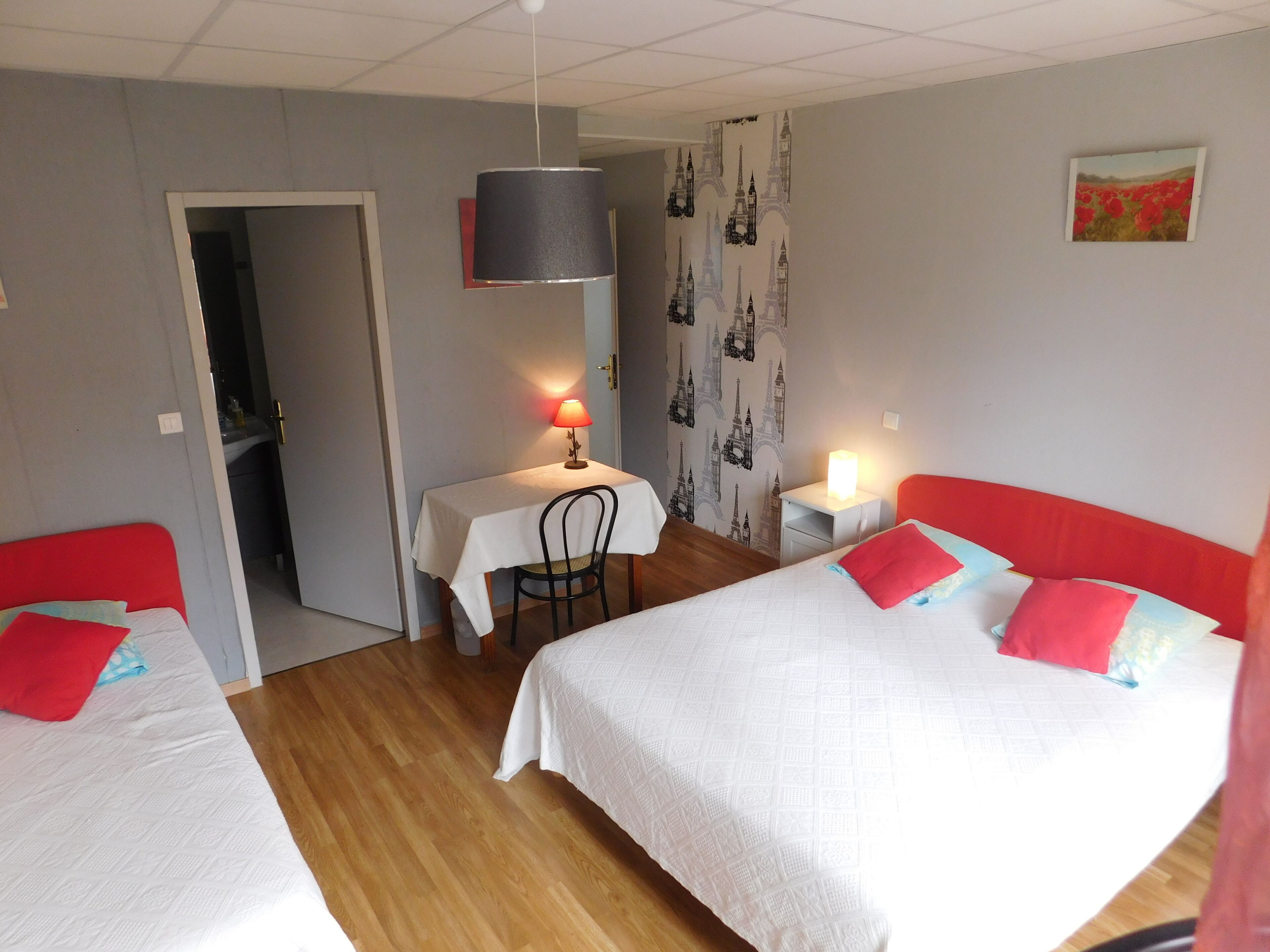 A room with two beds, a desk, a chair, and a lamp.