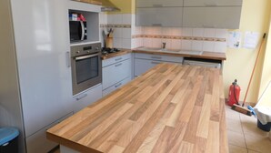 Una cocina con encimera de madera, electrodomésticos de acero inoxidable, armarios grises y salpicadero de azulejos.