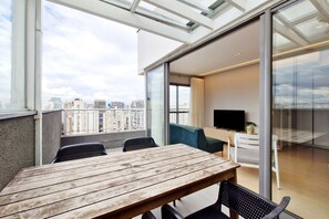 A balcony with a wooden table and chairs, a TV, and a view of the cityscape. - Nex One (São Paulo)