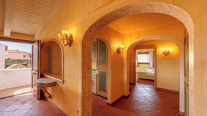 A corridor with arches, a window, and a door leading to a room. - NG Collection Cala del Faro 206 (Arzachena)