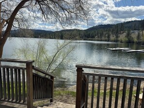 Blick auf einen See mit einem Holzsteg und einem Haus im Hintergrund.