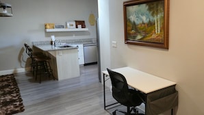 Una piccola cucina con zona pranzo, un quadro appeso al muro e una scrivania.