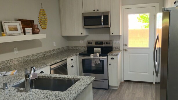 Una cucina con ripiani in granito, elettrodomestici in acciaio inossidabile e una porta bianca.