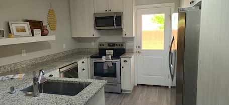 A kitchen with granite countertops, stainless steel appliances, and a white door.. Charming Ivins Retreat - Beautiful 3BR Home In Heart of Southern Utah