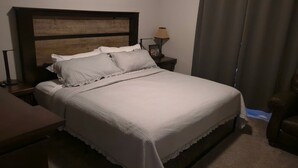 Un letto rifatto con un poggiatesta, una lampada da comodino e una sedia in una camera d'albergo.