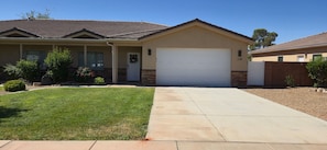 A single-story house with a front garage, a well-maintained lawn, and a clear sky.