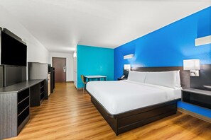 Ein Hotelzimmer mit Bett, Schreibtisch, Fernseher und einem kleinen Tisch.