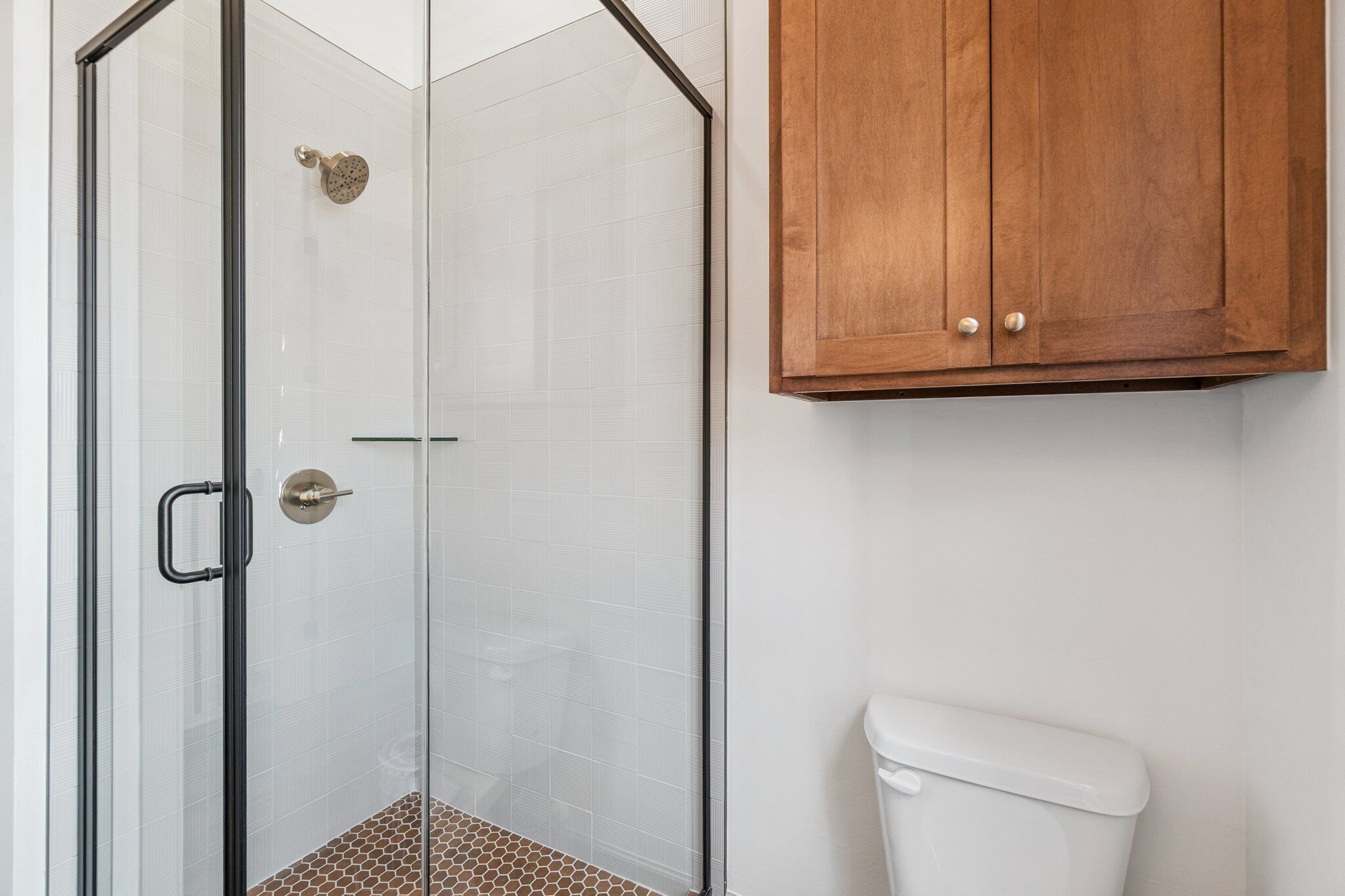 Une salle de bain avec une douche à parois de verre, des toilettes blanches et des meubles en bois.