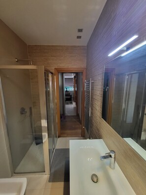 A modern bathroom with a glass shower enclosure, a white sink, and a large mirror. - Andrew's House (Napoli)
