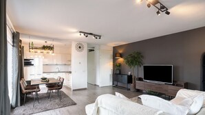 Un salon moderne comprenant un canapé, un téléviseur à écran plat et un coin repas avec une table et des chaises.