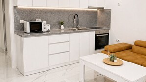 Een moderne keuken met witte kasten, een inbouwmagnetron, een spoelbak en een fornuis.