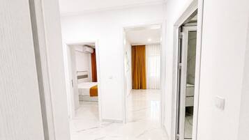 Een hotelgang met een bed, een badkamer en een glazen deur naar een balkon.