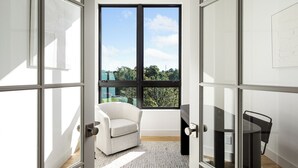A room with a large window, a white chair, a black table, and a glass partition. - Downtown Traverse City Penthouse w/ Private Rooftop (Traverse City)