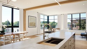 A spacious kitchen with a large island, modern appliances, and large windows offering views of the city. - Downtown Traverse City Penthouse w/ Private Rooftop (Traverse City)
