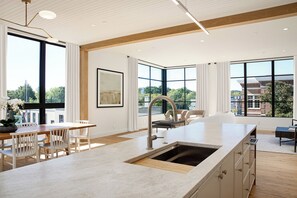 A spacious kitchen with a large island, modern appliances, and large windows offering views of the city. - Downtown Traverse City Penthouse w/ Private Rooftop (Traverse City)