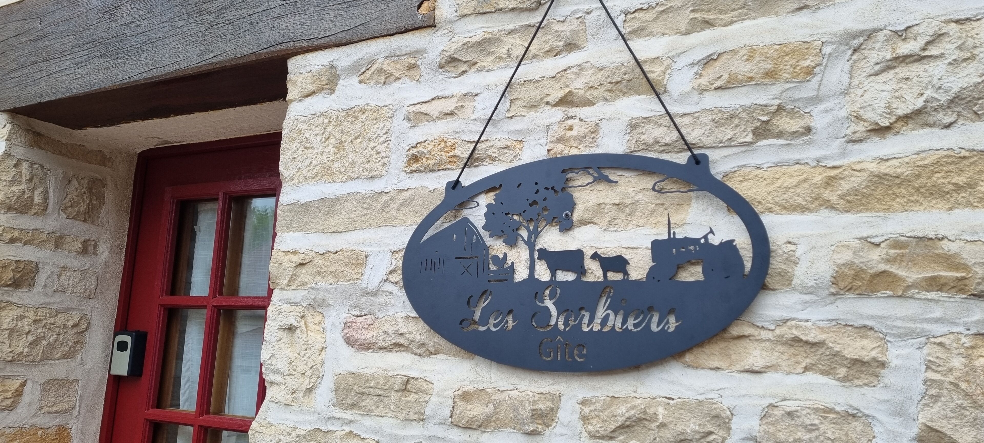 Kivimuuri, jossa on roikkuva kyltti, jossa lukee: »Les Sarbiers Gîte».