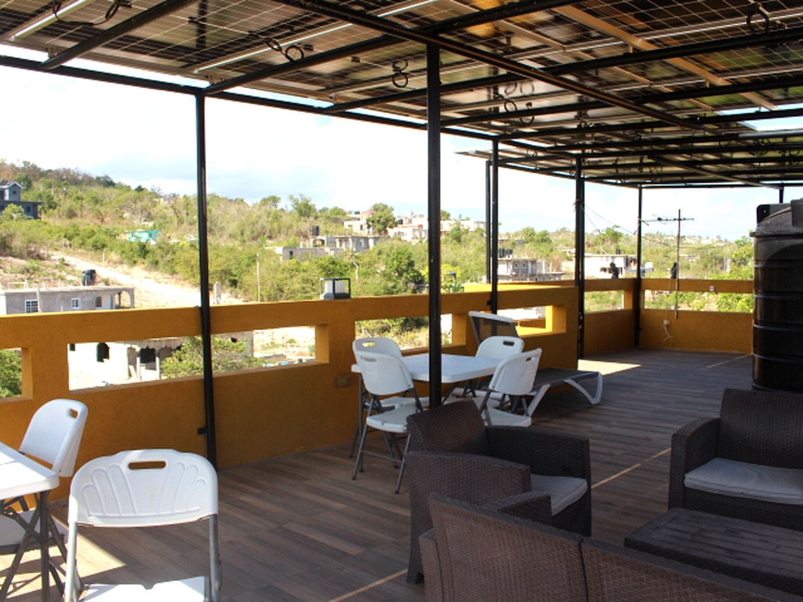 An outdoor patio area with a view of the surrounding landscape, featuring a table and chairs, and a large water tank.