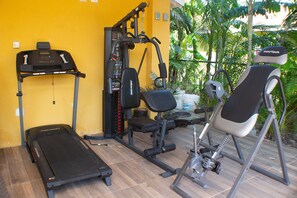 A gym with a treadmill, weight machines, and exercise chairs. - The Vista Inn Studio #1 (Falmouth)