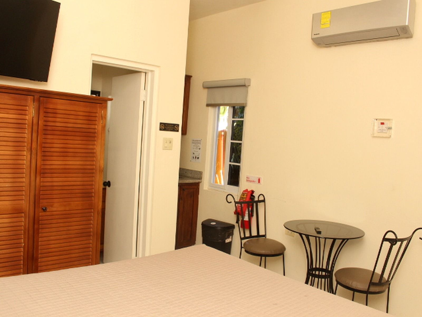 A room with a bed, a table with chairs, a window with a view, and a wall-mounted air conditioner.