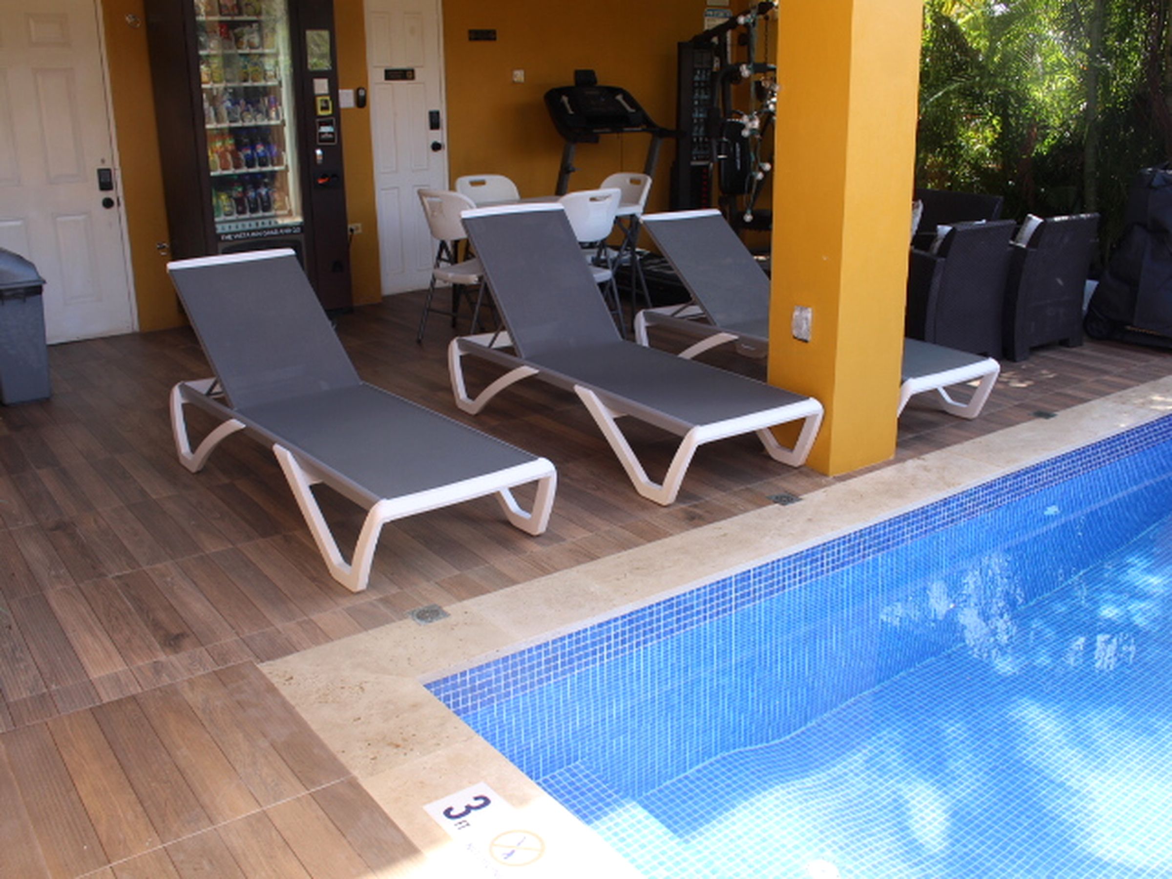 A pool area with lounge chairs and a water fountain.