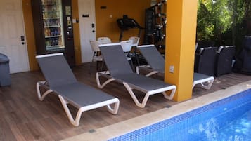 A pool area with lounge chairs and a water fountain.