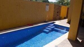 A swimming pool with steps leading into it, a yellow wall, and a sign indicating pool rules. - The Vista Inn Studio #2 (Falmouth)
