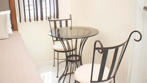 A room with a bed, a round glass table, two chairs, and a window with blinds. - The Vista Inn Studio #2 (Falmouth)