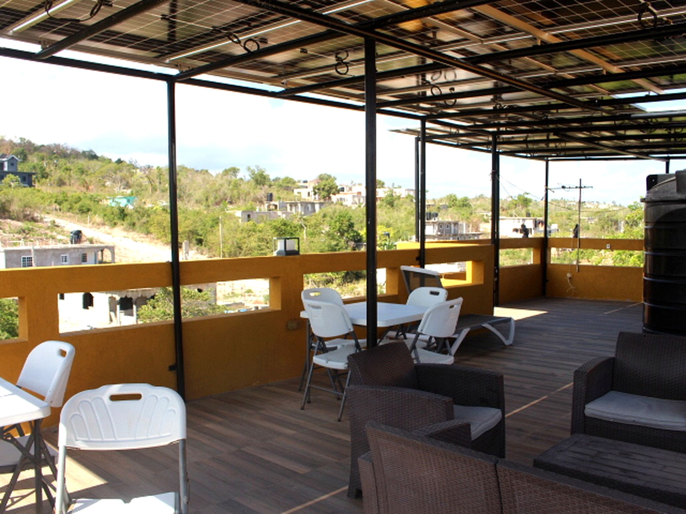 An outdoor patio with seating, a view of the surrounding area, and a metal roof structure.