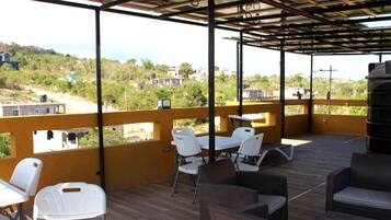 An outdoor patio with seating, a view of the surrounding area, and a metal roof structure.