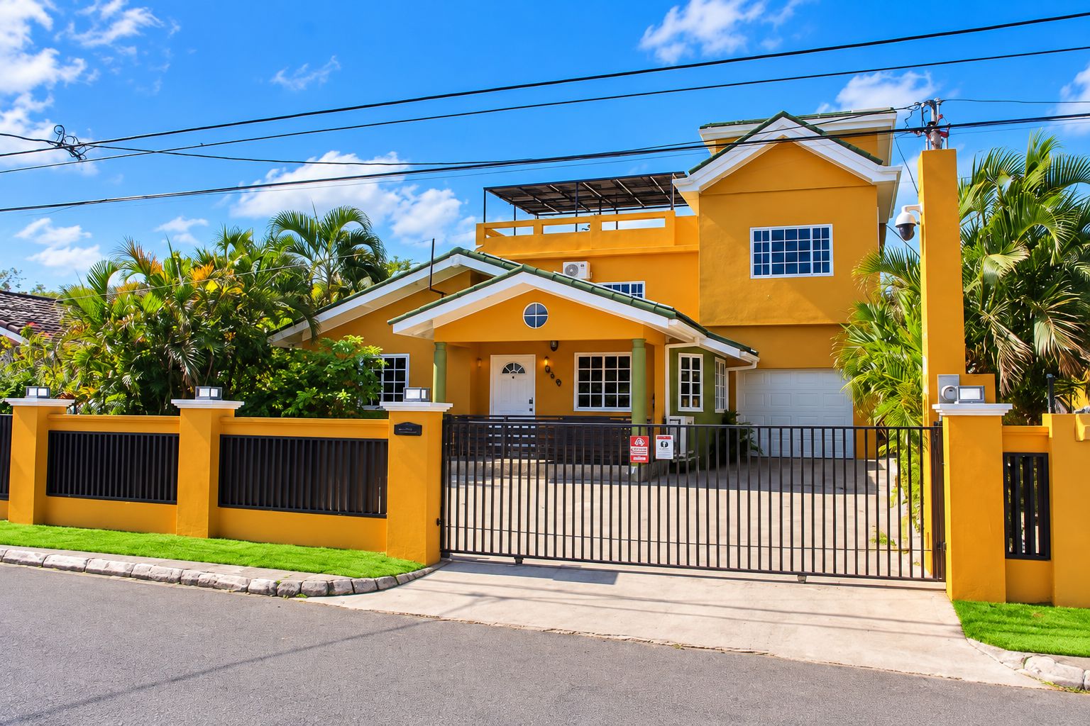 A yellow two-story house with a gated entrance, a garage, and a small porch.