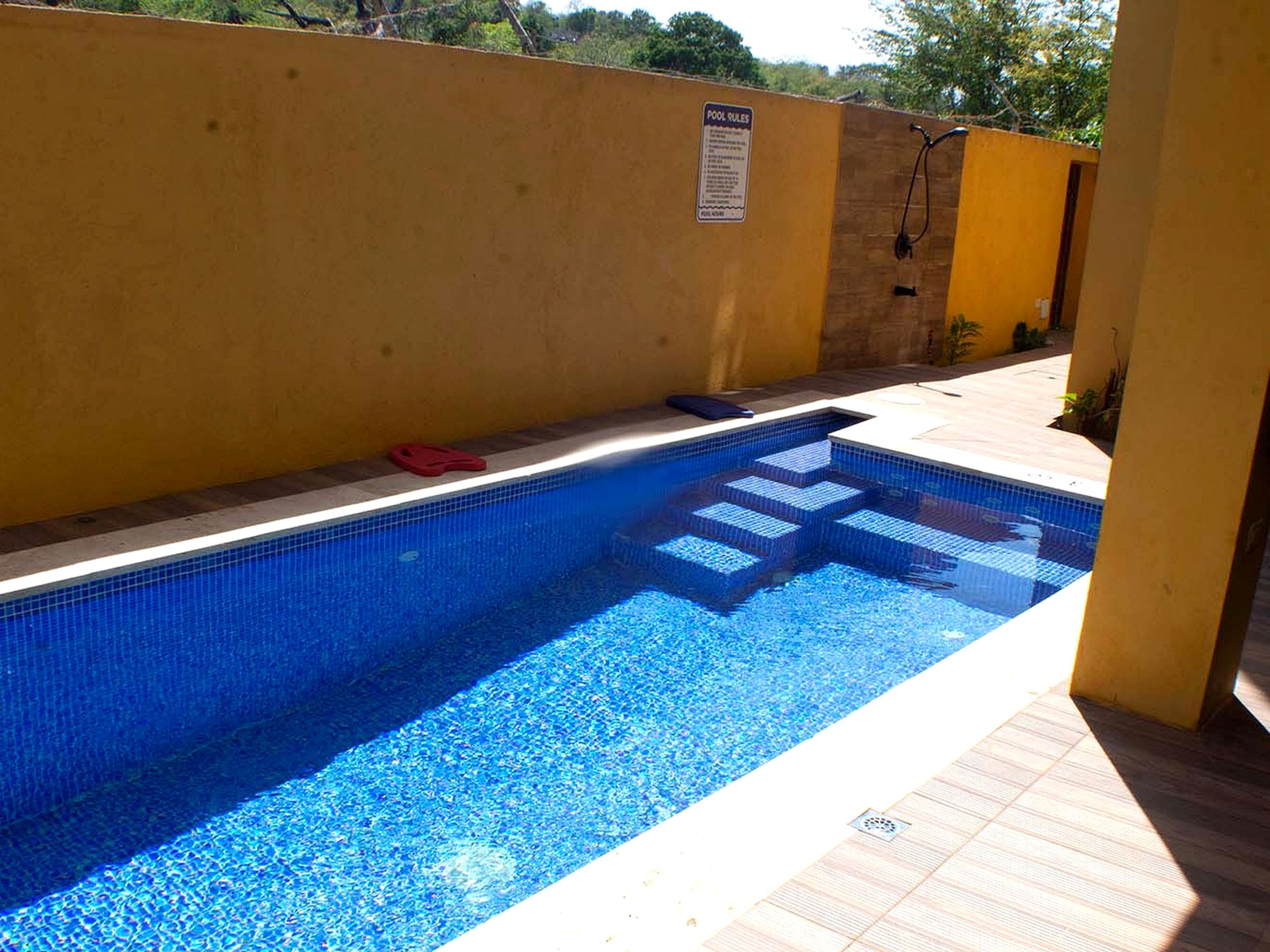 Una piscina con borde de azulejos y un letrero con las normas de la piscina.