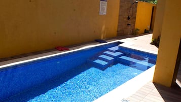 Una piscina con borde de azulejos y un letrero con las normas de la piscina.