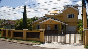 A two-story house with a gated entrance, a small porch, and a garage. - The Vista Inn Studio #2 (Falmouth)