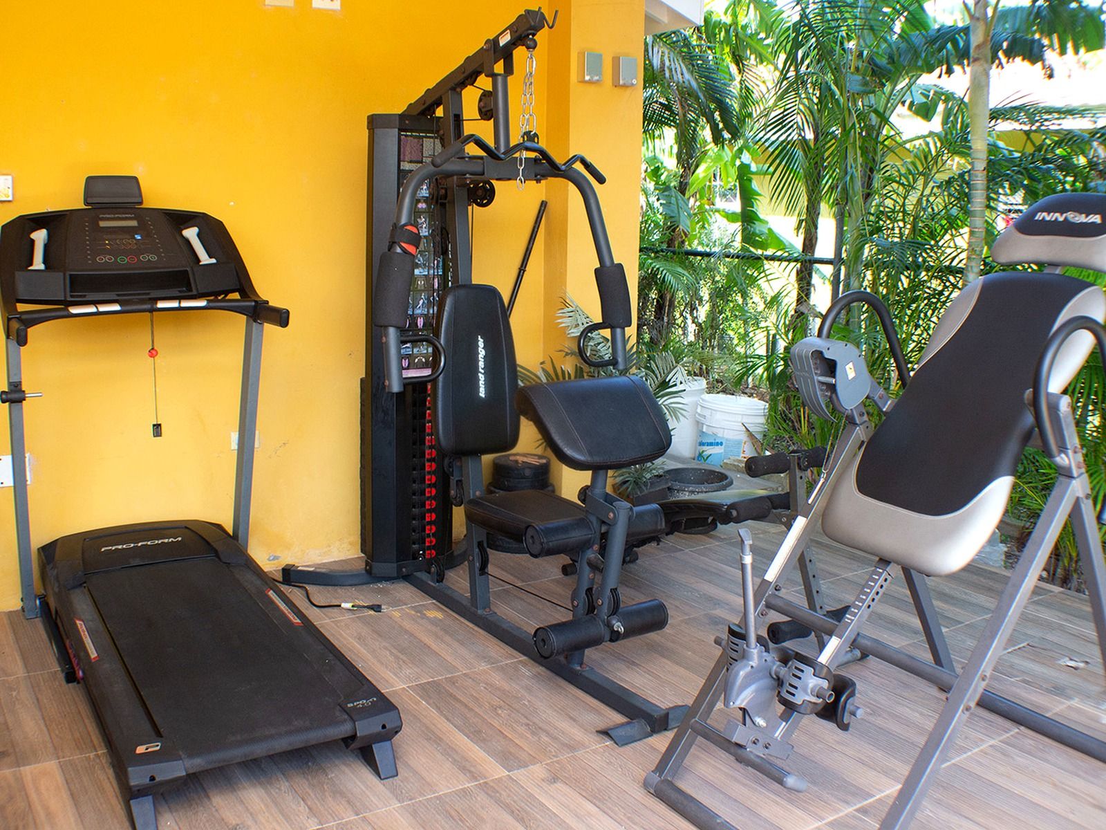A gym with a treadmill, weight machines, and a rowing machine.
