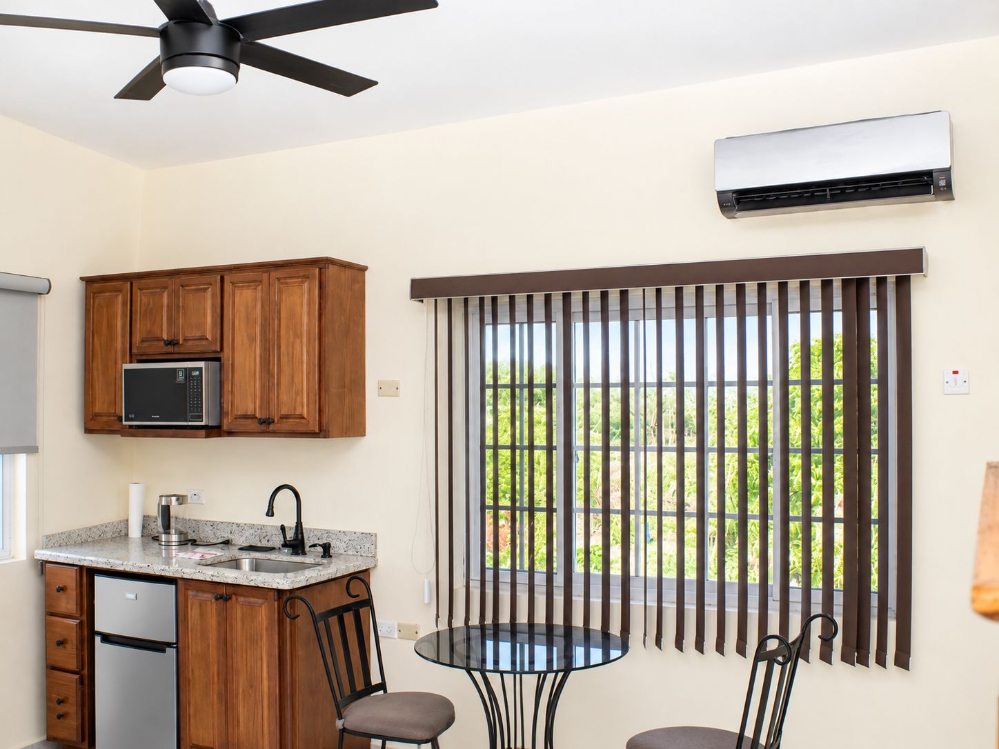 A kitchen with wooden cabinets, a microwave, a sink, and a ceiling fan.