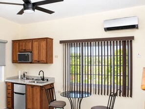 Una cocina con armarios de madera, microondas, pileta y ventilador de techo.