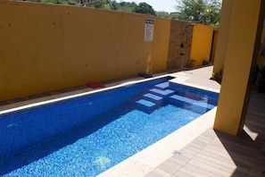 A swimming pool with steps leading into it, a yellow wall, and a sign indicating pool rules. - The Vista Inn Studio #3 (Falmouth)