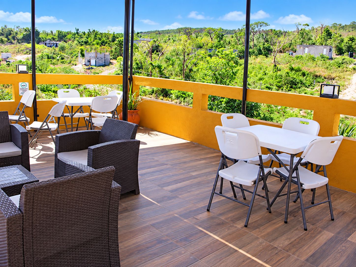 Un patio al aire libre con mobiliario de mimbre y vistas a un paisaje verde.